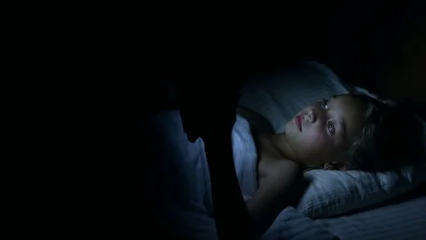 Little Girl at Night Lies in Her Bed and Watches Something on Tablet Computer Stock Footage