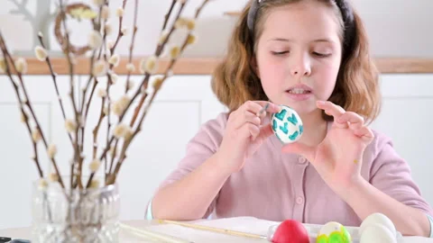 A little girl paints eggs for Easter. Child schoolboy of European appearance and Stock Footage 170705039