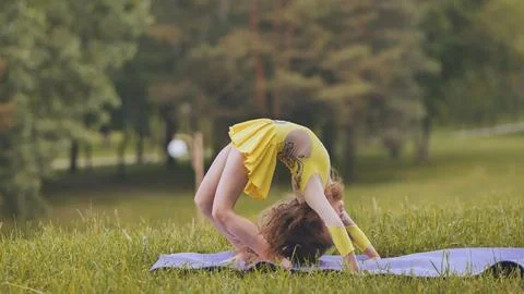A little girl performs the elements of rhythmic gymnastics in the park. Fotos Stock