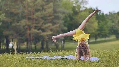A little girl performs the elements of rhythmic gymnastics in the park. Stock Photos
