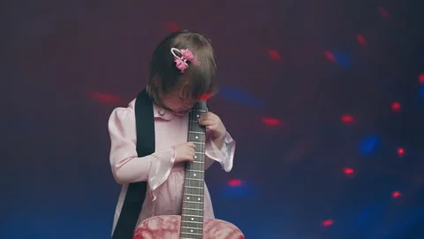 Little girl in a pink vintage dress plays an acoustic guitar like a double bass Stock Footage