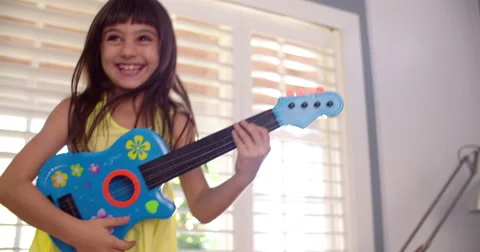 Little girl playing a guitar in the lounge Stock Footage