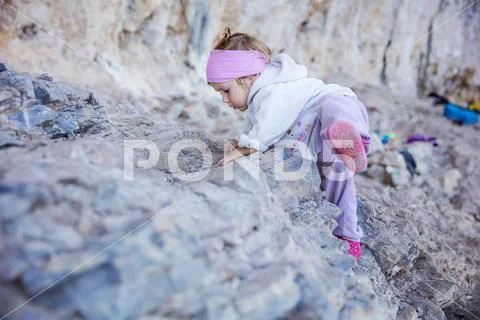 Little girl playing on rocks near climbing sector Stock Photos