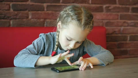 Little girl is playing with smartphone Stockbeeldmateriaal 87694792