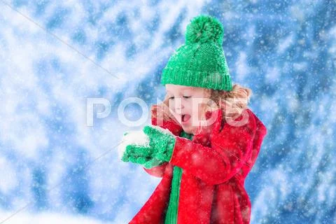 Little girl playing in snowy park Stock Photos