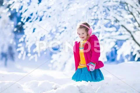 Little girl playing in snowy winter forest Stock Photos