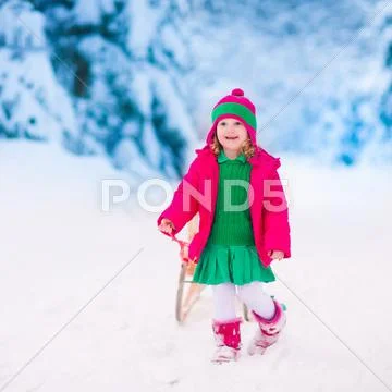 Little girl playing in snowy winter forest Stock Photos