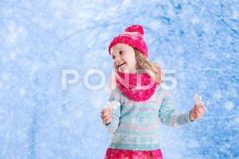 Little girl playing with toy snow flakes in winter park Stock Photos