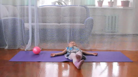 A little girl plays the fool, doing exercises, yoga, play with a ball Video stock 35608053
