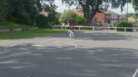 Little girl practices highway code on bicycle in urban playground. 動画素材 318961316