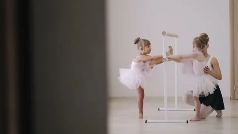 Little girl practicing choreographic elements on ballet barre with help of Stock Footage 152862833