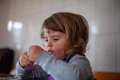 Little girl practicing problem-solving with a fun puzzle Stock Photos
