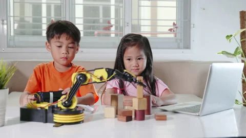 Little girl program code to robot with laptop and boy test with remote control Stock Footage 228113680