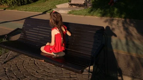 Little Girl in Red Siting on Bench and Watching People Jogging Stock Footage