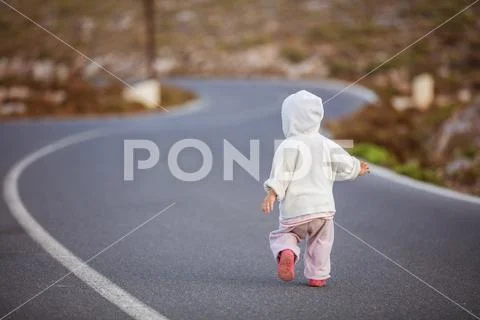 Little girl running down road in countryside Stock Photos