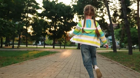 Little girl running through park sunset, happy family, running foot along road Stock Footage 258987341