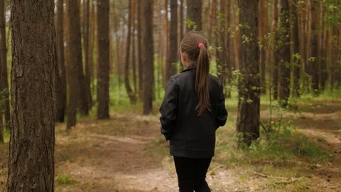 The little girl runs along the path road in the pine forest. Dressed in the Video stock 129795853