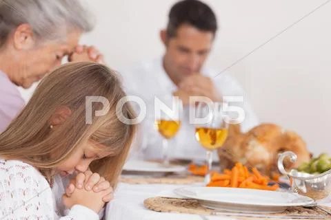 Little girl saying grace with family Stock Photos