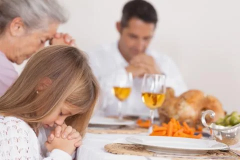 Little girl saying grace with family Stock Photos