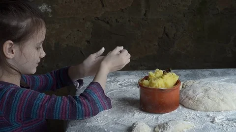 Little girl sculpts patties with potatoes, and sprinkle them with flour Stock Footage