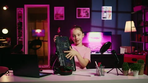 Little girl showcasing computer peripherals to fans on gen Z online channel Stock Footage 255621978