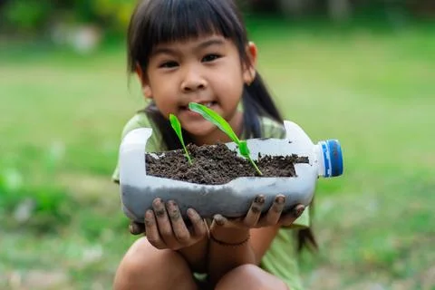 Little girl shows saplings grown in recycled plastic bottles.  Stock Photos