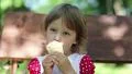 Little girl sits on the bench and eats ice cream HD Footage