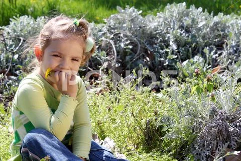 Little girl sits in grass and thinks.JPG Stock Photos