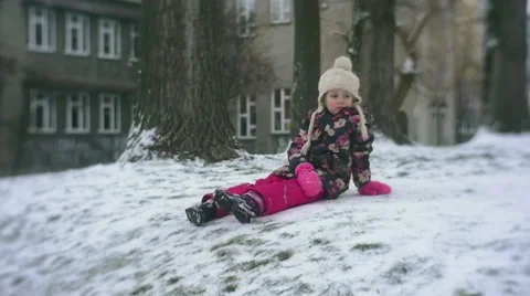 Little Girl is Sitting on a Snow on a Ground Outdoors Yard in Winter Slow Stock Footage 59771832
