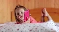 Little girl with smartphone lies on the bed HD Footage