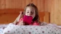 Little girl with smartphone lies on the bed HD Footage