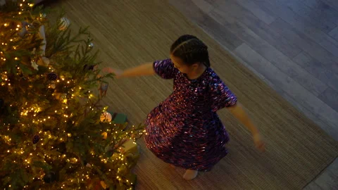 Little girl spinning around while dancing in room decorated with Christmas tree. Stock Footage 201249342