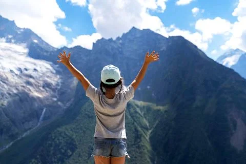 A little girl stands in the mountains and raises her hands to the sky Stock Photos