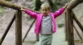 Little girl stands on a wooden bridge and does dance moves HD Footage