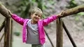 Little girl stands on a wooden bridge and smiles HD Footage