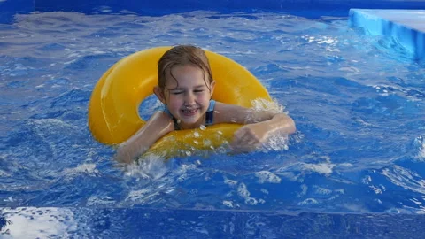 A little girl swims in the pool using a yellow inflatable ring. the child learns 스톡 동영상 201357853