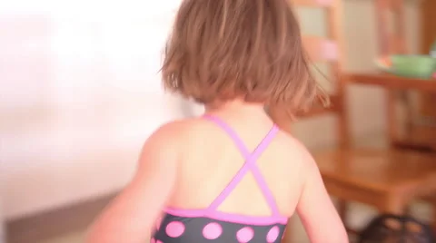 Little girl in a swimsuit runs around th... | Stock Video