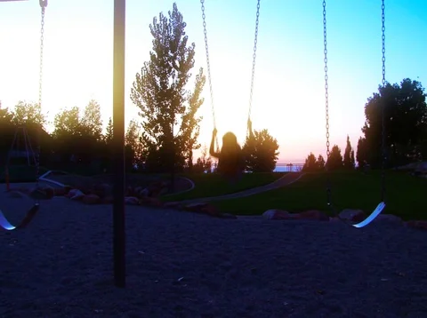 Little girl swinging at sunset. Stock Footage