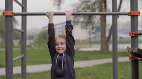 Little girl try to do pull ups on the bar in the park Stock Footage 131156613