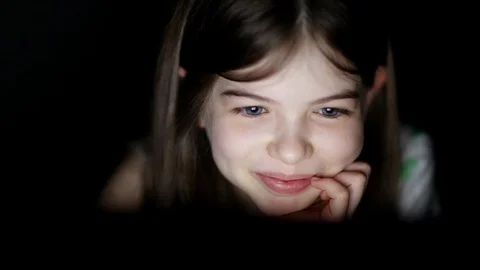 A little girl uses a laptop at night, plays games, watches videos Stock Footage