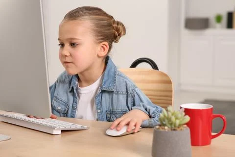 Little girl using computer at table in room. Internet addiction Stock Photos