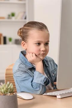 Little girl using computer at table in room. Internet addiction Stock Photos