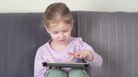 Little girl using digital tablet to learn while sitting on the sofa. Stock Footage 149078725