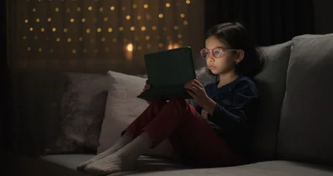 Little girl using digital tablet watching cartoons at night Stock Footage 243066952