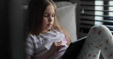 Little girl using digital tablet at home. Child on social media. 動画素材 335643836