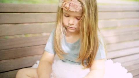 Little girl using smartphone sitting on bench park soft light Stock Footage 314337075