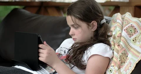 Little Girl Using Tablet Computer on Sofa on Terrace Stock Footage 64651339