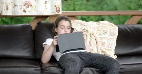 Little Girl Using Tablet Computer on Sofa on Terrace Stock Footage 64655817