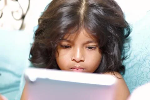 Little girl using a tablet computer at home Selective focus Photos