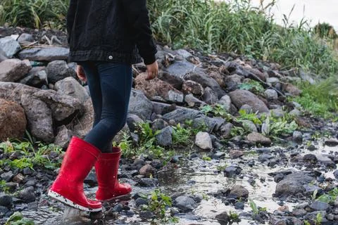Little girl walking down a small stream with her red boots Stock Photos